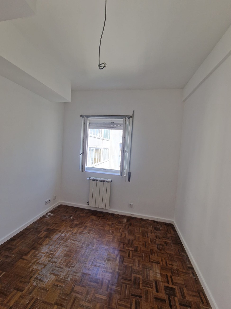 Quarto remodelado com paredes brancas e chão em taco